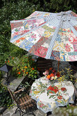 DIY parasol over garden table set with bouquet of flowers and strawberry cake