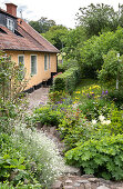 Blick auf Garten mit Wegen aus Kopfsteinpflastern und auf Haus