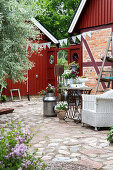 Patio area with rattan armchair and vintage sewing machine table on stone floor