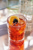 A Negroni, garnished with orange and blackberry