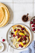 Crepes with chocolate spread, cherries, oranges and pistachios