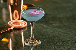 A cocktail with a purple flower garnish