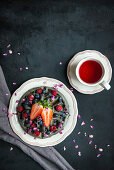 Schwarze Waffeln mit Beeren und eine Tasse Tee