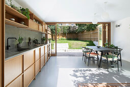 Fitted kitchen with wooden fronts and dining area; view into the sunny garden