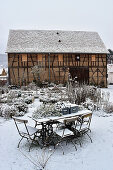 Snow-covered cottage garden in front of barn