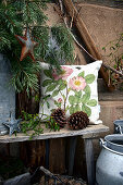 Rustic seating area with cushions, pine cones and mistletoe outside wooden house