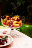 Italian fried pastry with cherries in a glass jar on a table in the garden
