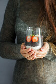 Hände halten Glas mit Chiapudding, Joghurt und Erdbeeren