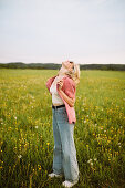 Glückliche junge Frau steht auf einer sommerlichen Blumenwiese