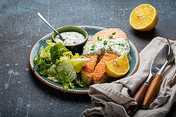 Healthy food meal cooked grilled salmon steak with white dill sauce and green salad leafs