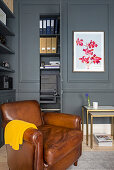 Brown leather armchair in corner of room with grey walls and moulding