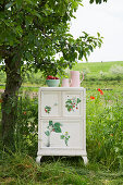 An upcycled bedside table with a strawberry design in a garden