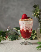 Berries and ice cream garnished with nuts and strawberries served on table near glass jars