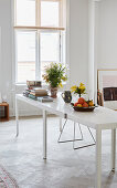 A long dining table made of two white tables in a light-flooded old building