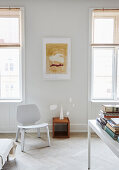 A designer chair and a mobile between two windows in the living room of an old building