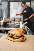 Delicious burger placed on table on background of chef preparing fast food in food truck kitchen
