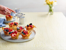 Summer berry tartlets dusted with powdered sugar