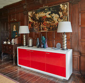 Modern sideboard with table lamps, and a large Painting hung above it in a room with dark coffered wood paneling