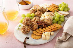 Cheese balls on a cheese board with crackers and grapes