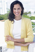 Dark-haired woman in white top and yellow cardigan