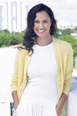 Dark-haired woman in white top and yellow cardigan