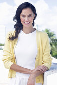 Dark-haired woman in white top and yellow cardigan