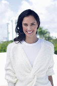 Dark-haired woman in white top and white wrap-around cardigan