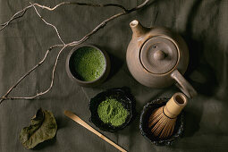Traditional japanese hot green frothy tea matcha in ceramic cup, powdered matcha, teapot and bamboo whisk
