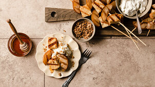 Grilled pound cake and pears on a plate with whipped cream, honey, and a sprinkle of granola