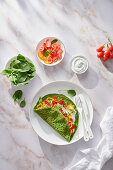 Spinach creppe with tomato and pepper slices and sour cream