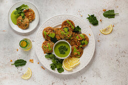 Herbal fritters garnished with healthy green sauce parsley and lemon slices on white table