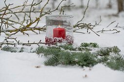 Stern aus Tannenzweigen und Windlicht im Schnee