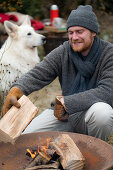 Man puts log in the fire bowl