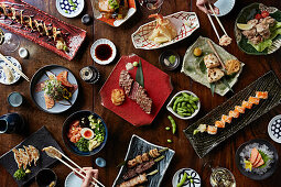 Selection of Japanese dishes: Sushi, teriyaki skewers, and gyoza