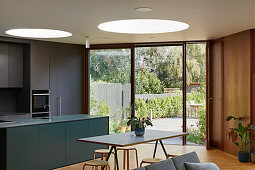 Open kitchen and dining area in front of a patio door in a living room with round skylights