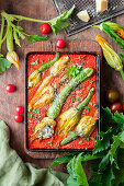 Roasted zucchinis in tomato sauce with flowers stuffed with cream cheese and herbs