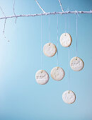 Christmas biscuits with white icing hanging from a branch