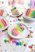 Rainbow cake cut into pieces and served on plates