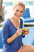 Blonde Frau in blauem Shirt mit Dessert in der Hand