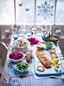 Christmas table laid with baked salmon and various side dishes