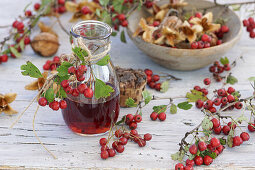 Hawthorn liqueur, in the background a stone bowl filled with hawthorn and beechnuts