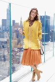 Long haired woman in orange skirt, yellow knit sweater and short coat