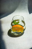 Glass of refreshing water with orange and mint in sunny day