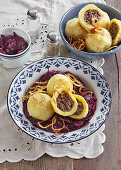 Potato dumplings stuffed with white sausage on red cabbage
