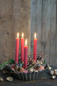 Baking tin filled with candles stuck in apples, gilded walnuts, and acorns