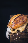 Crusty bread on a wooden board against a black background