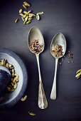 Cardamom seeds in a mortar and on two spoons