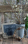 Plum blossom twigs in a zinc pot, wreath made of larch twigs and slate