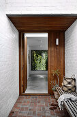 Entrance area with white painted brick walls and wooden door, bench in the foreground