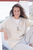 Long haired woman in light casual knitted jumper and trousers